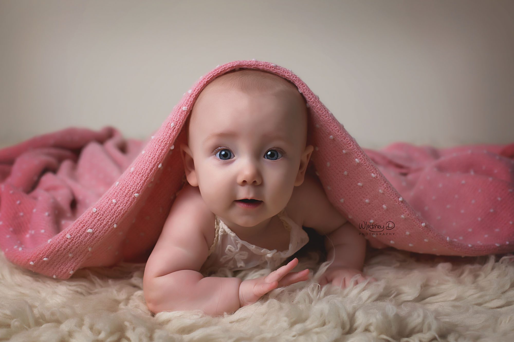Six month Baby Girl in Lace Romper, blanket over her in a photography studio in Conway, Arkansas