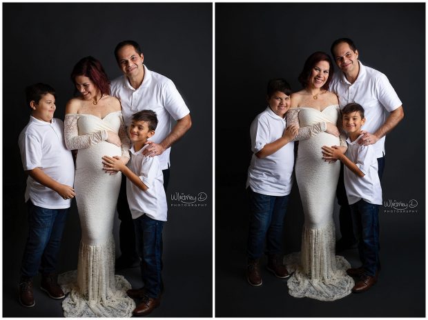Pregnant mom in white lace maternity gown with family on gray backdrop at Whitney D. Photography in Conway, Arkansas